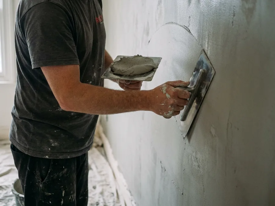 Plasterer skimming a wall with a trowel